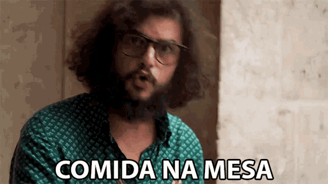 a man with glasses and a beard is saying comida na mesa