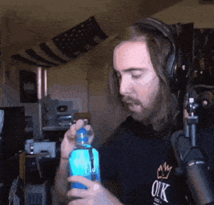 a man wearing headphones holds a blue bottle that says ok