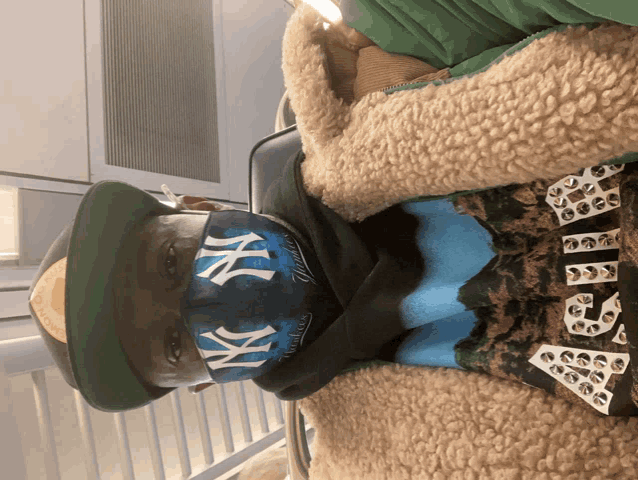 a man wearing a new york yankees face mask and a hat