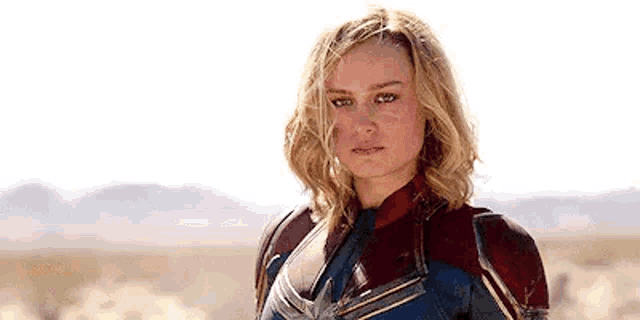 a woman in a superhero costume is standing in a desert .