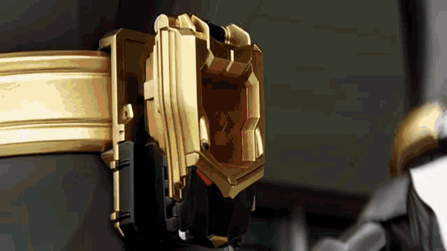 a close up of a gold and black object with a red light coming out of it