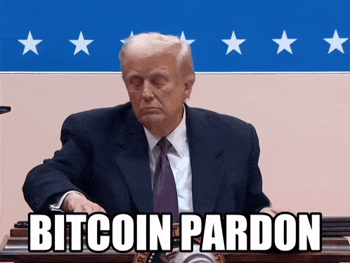 a man in a suit and tie is sitting at a podium with the words bitcoin pardon written below him