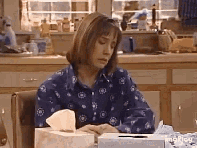 a woman is sitting at a table with a box of tissues and a box of tissues .