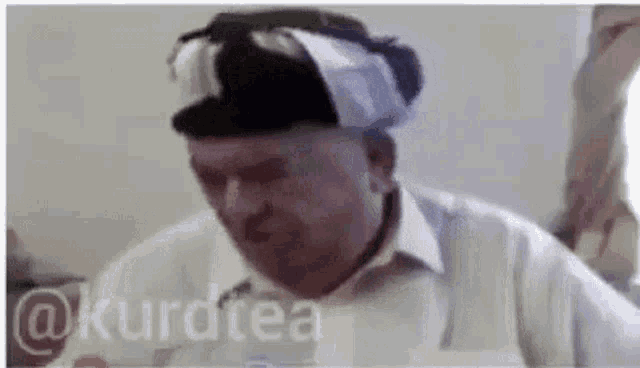 a man wearing a turban is making a funny face while sitting at a table .