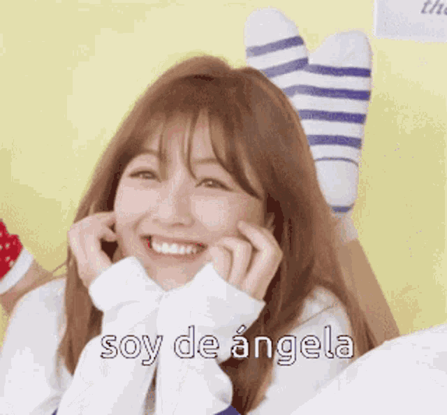 a girl with striped socks on her head is smiling and saying soy de angela