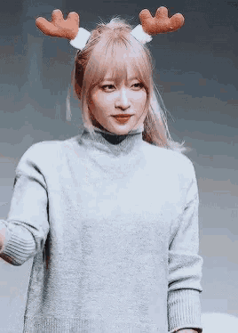 a woman wearing a reindeer headband and a sweater