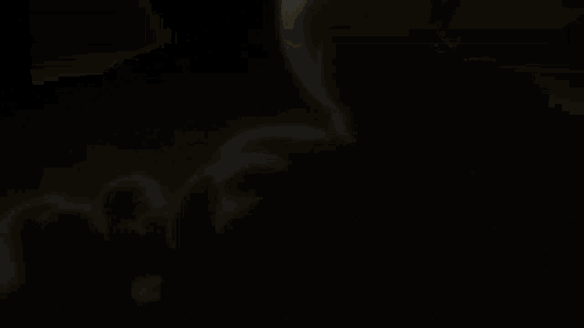 a person is standing in a dark room with a yellow light coming out of them