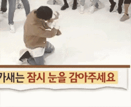 a man is kneeling down in front of a group of people on a ice rink .