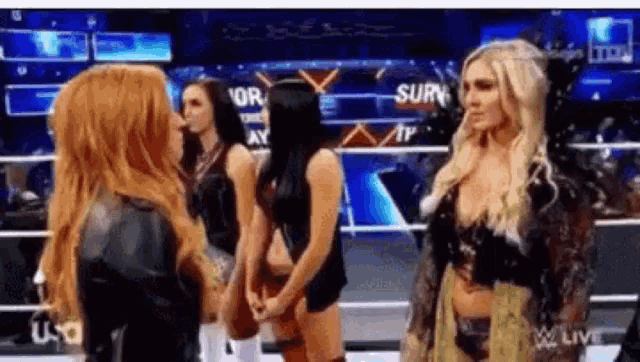a group of women are standing in a wrestling ring holding hands .