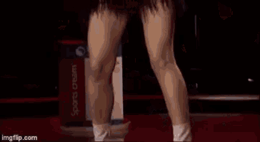 a woman with long hair is standing on a stage with her arms outstretched in front of a red background .