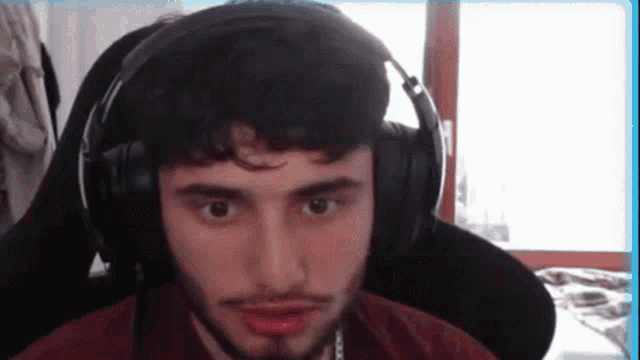 a man with a beard wearing headphones is sitting in a chair .