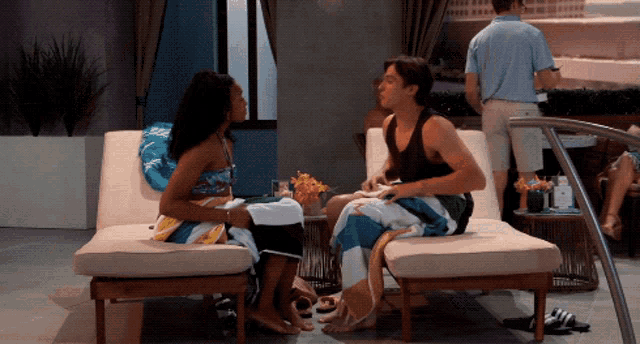 a man and a woman sitting on lounge chairs talking
