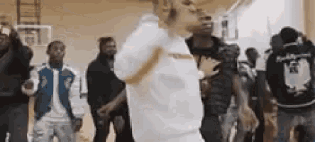 a man is dancing in front of a crowd of people in a basketball court .