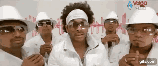 a group of men wearing white hats , sunglasses , and goggles are standing next to each other .