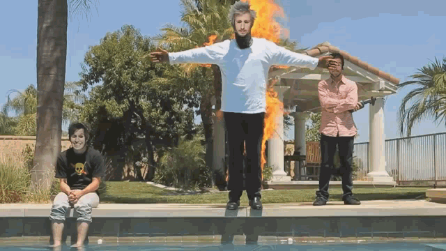 a man in a white shirt with a skull on it is standing in front of a pool