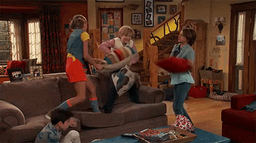 a family is having a pillow fight in the living room .