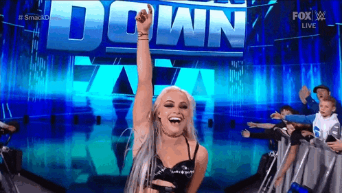 a woman is raising her fist in the air in front of a crowd of people .