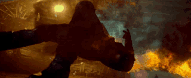 a man is flying through the air in a dark room with fire behind him .
