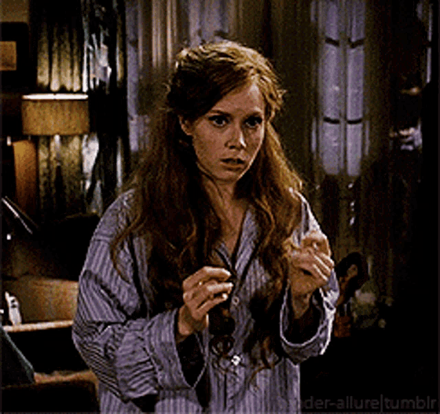 a woman in a striped shirt is standing in front of a window in a room ..