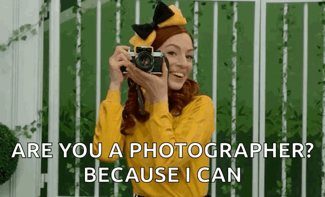 a woman in a yellow shirt is holding a camera and asking if she is a photographer because i can .