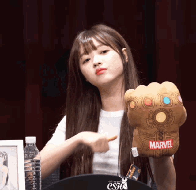 a girl is holding a stuffed infinity gauntlet from marvel