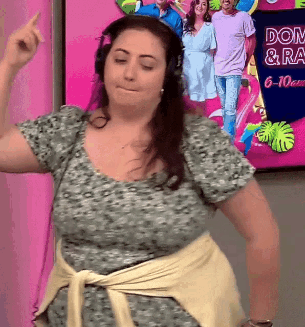 a woman wearing headphones is dancing in front of a sign that says dom & lg