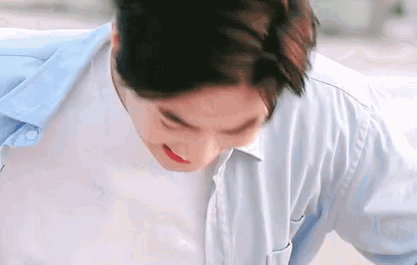 a close up of a man 's face wearing a blue shirt and a white shirt .