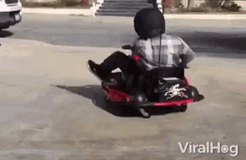 a man in a helmet is riding a go kart on the street .