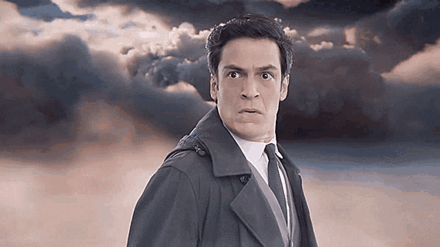 a man in a suit and tie is making a funny face in front of a cloudy sky