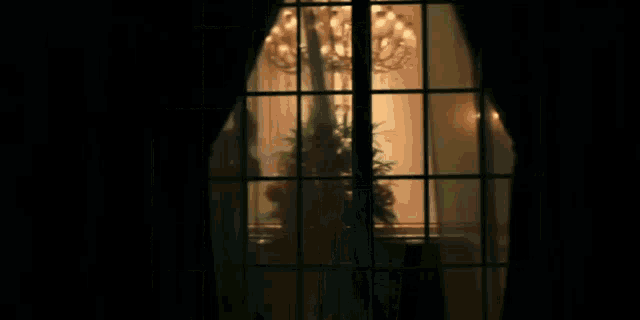 a dark room with a chandelier and a window