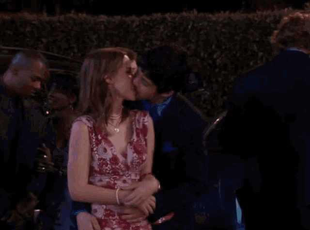 a man kisses a woman on the cheek in front of a group of people