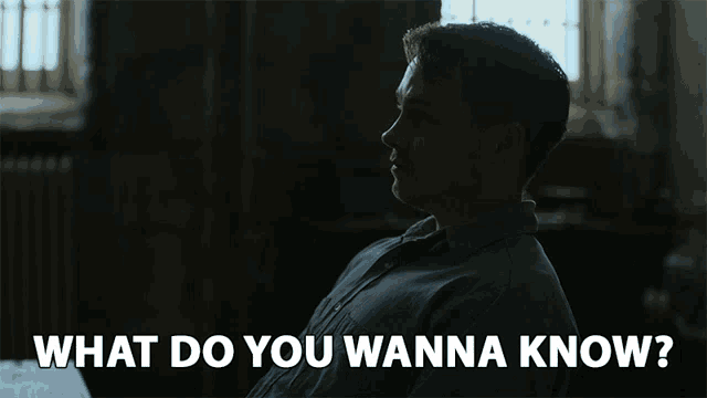 a man sitting in a dark room with the words " what do you wanna know " behind him