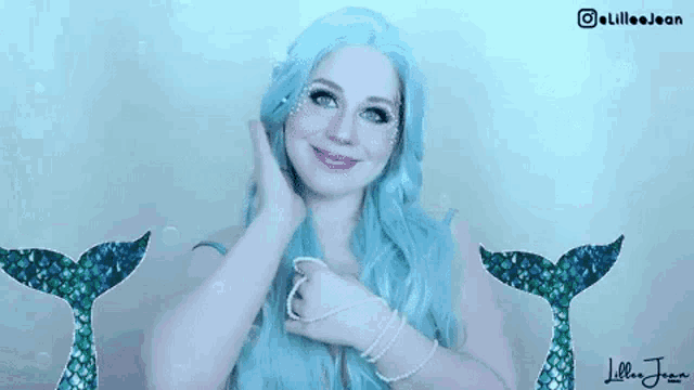 a woman with blue hair is dressed as a mermaid and has two mermaid tail behind her .