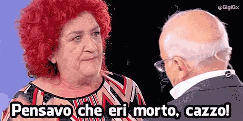 a woman with red hair is talking to a bald man with the words pensavo che eri morto cazzo