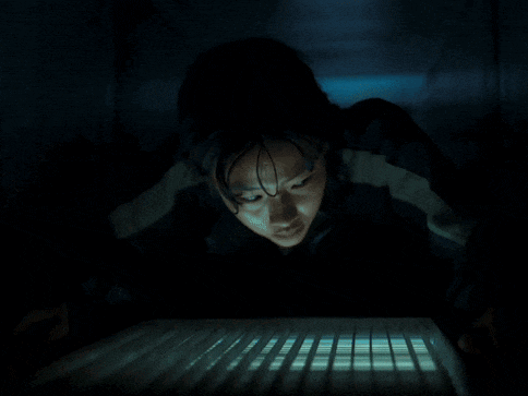 a woman in a dark room is looking at a keyboard