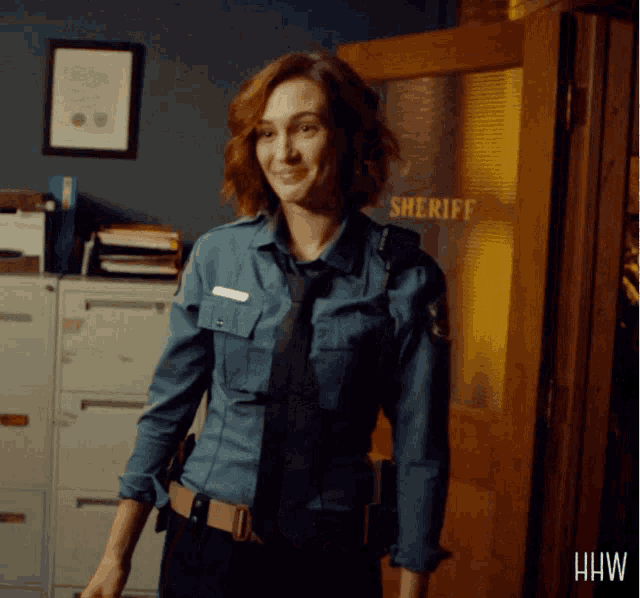 a woman in a sheriff uniform stands in front of a door that says sheriff on it