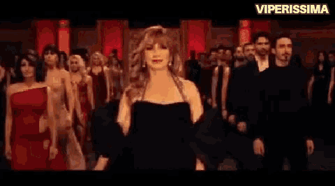 a woman in a black dress is dancing in a crowd of people .