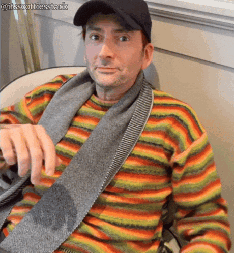 a man wearing a striped sweater and scarf is sitting in a chair ..