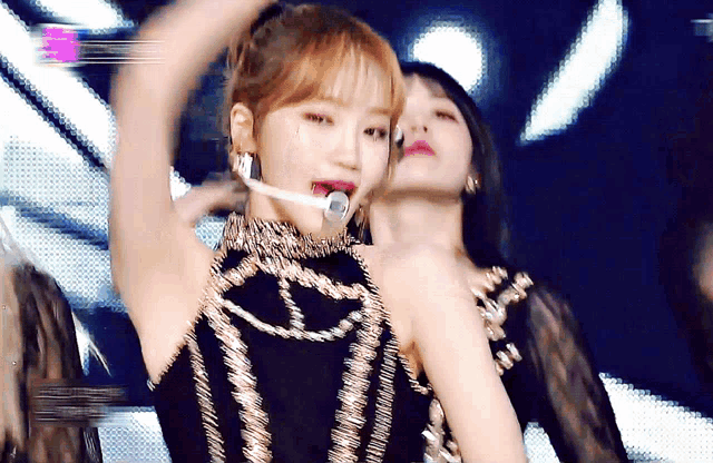 a woman in a black and gold dress is holding a microphone