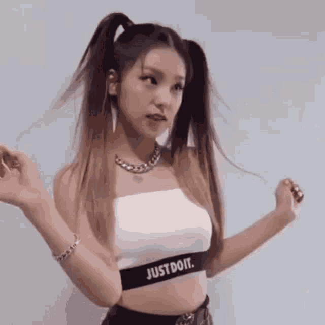 a woman with pigtails is wearing a white crop top with a just do it waistband .