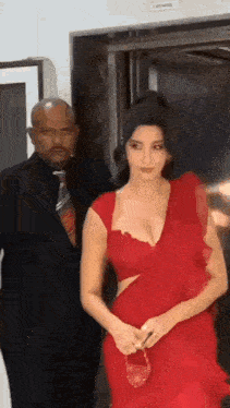 a woman in a red dress is standing in front of a man in a suit and tie .