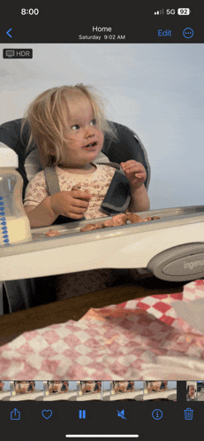 a baby in a high chair with a bottle of milk