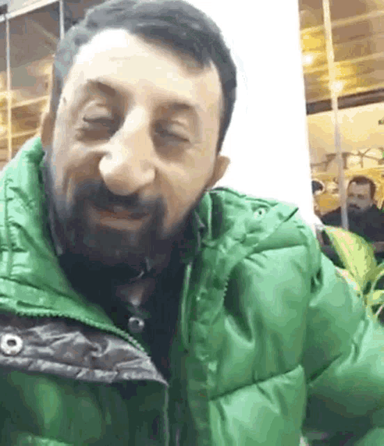 a man with a beard wears a green jacket