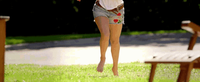 a woman in shorts and a white shirt is jumping in the air .