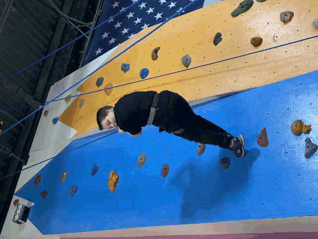 a person laying on a climbing wall with a rope