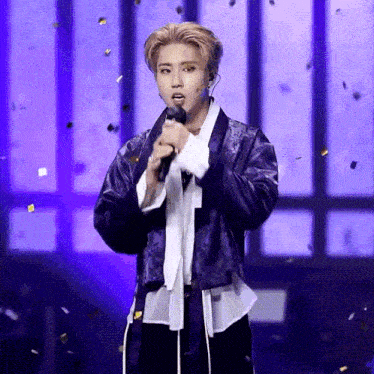 a man in a blue jacket is singing into a microphone