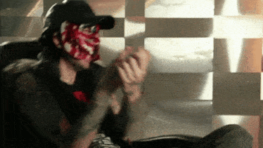 a man wearing a mask is sitting in a chair and clapping his hands