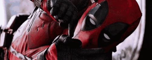 a close up of a person in a deadpool costume holding their finger to their lips .