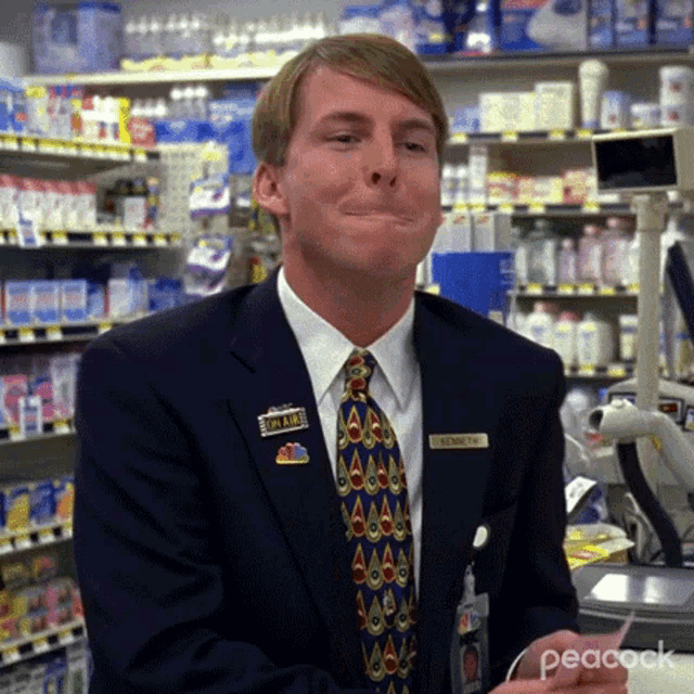 a man in a suit and tie is standing in a grocery store holding a receipt .
