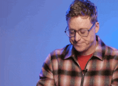 a man wearing glasses and a plaid shirt is using a laptop computer